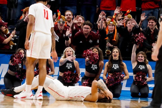 Houston's Emanuel Sharp (21) puts his head in his hands on the ground after he fouled out of the game as Texas A&M's cheerleaders and band members wave goodbye to him during the second round game between Texas A&M and the University of Houston in the 2024 NCAA Tournament at FedExForum in Memphis, Tenn., on Sunday, March 24, 2024.